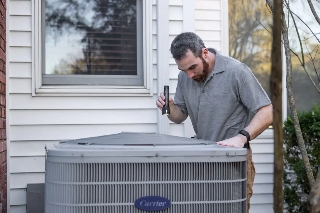 A technician inspecting an outdoor HVAC unit
