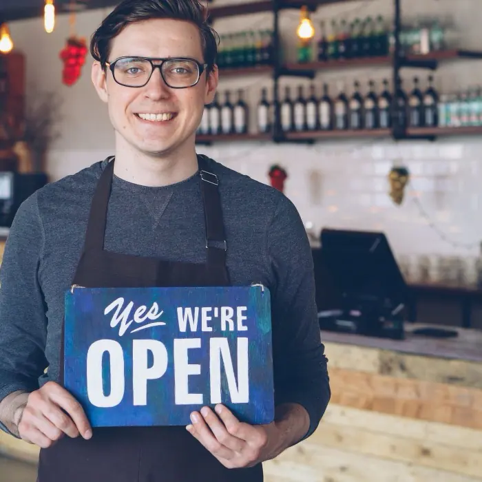 A shop owner outside their open business